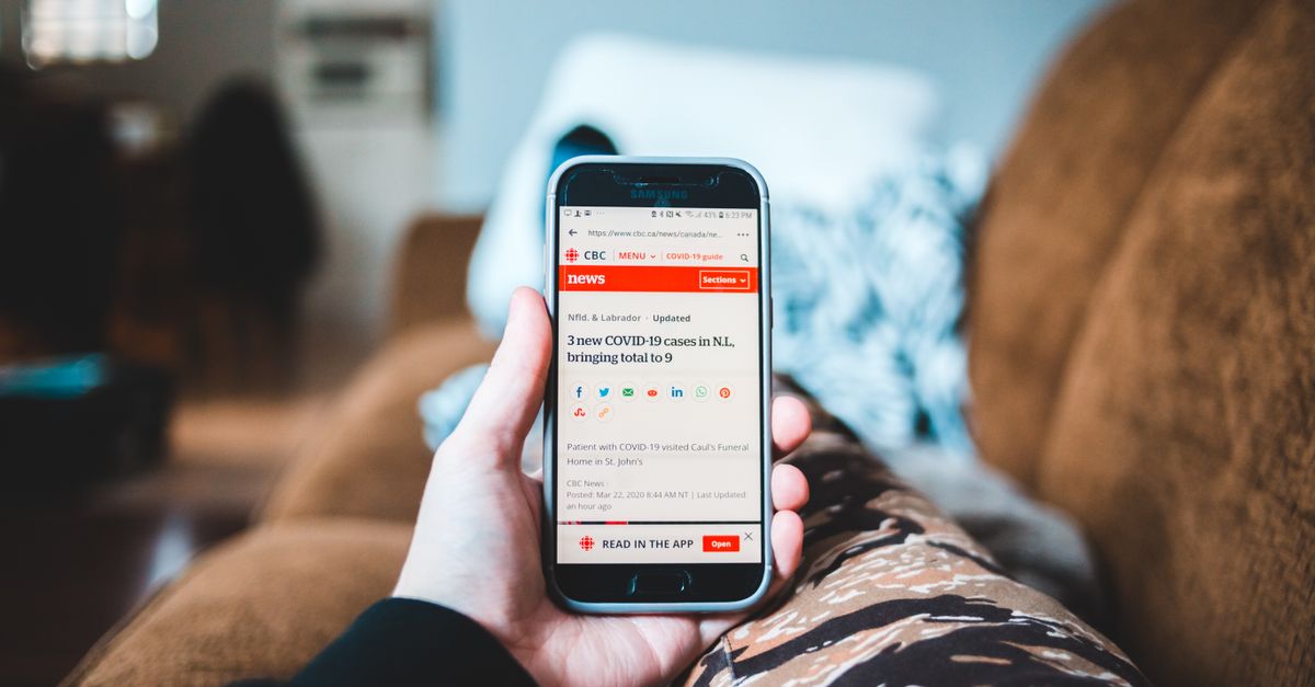 hand holding smartphone displaying stripped-down news article
