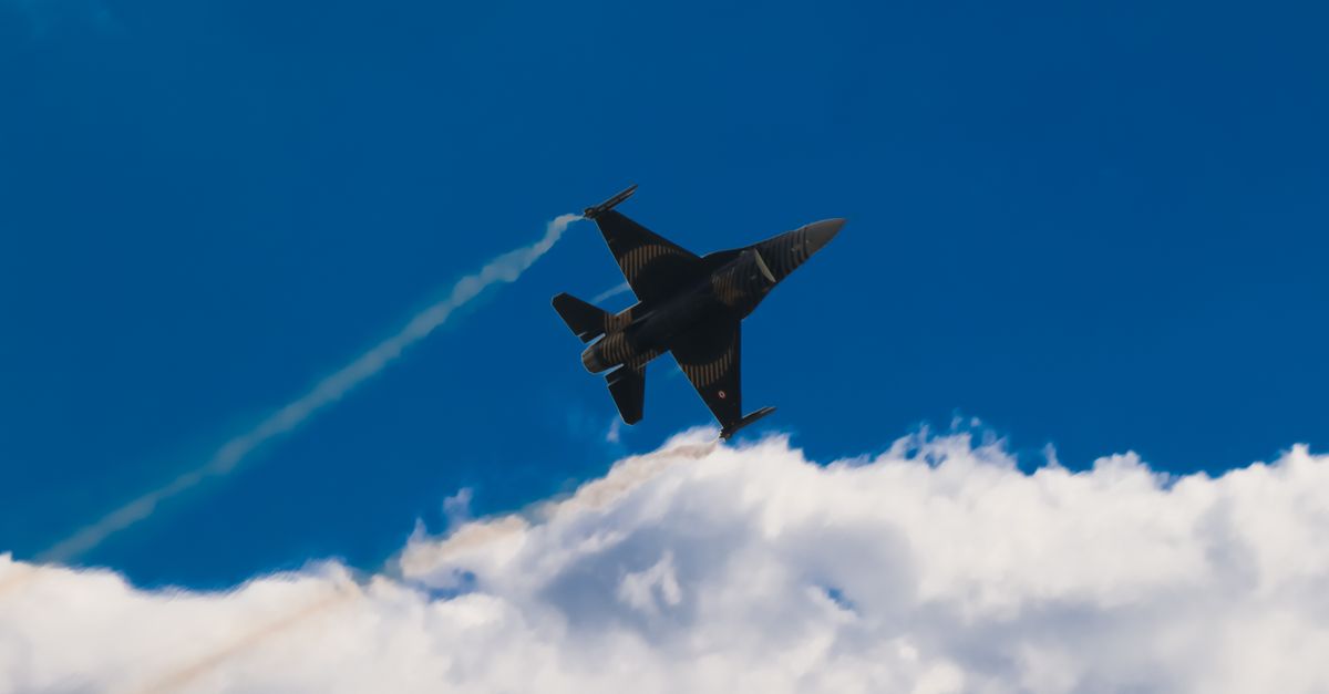 silhouette of a sleek supersonic jet over clouds with a data center tower in the background
